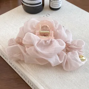 Détail d'une pince à cheveux en gaze rose avec pendentif coeur doré sur livre