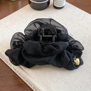 Vue détaillée d'une grande pince à cheveux en organza noir avec pendentif cœur doré