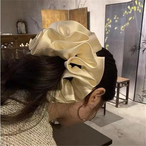 Chouchou géant en satin blanc cassé avec bords à volants sur les cheveux d'un mannequin