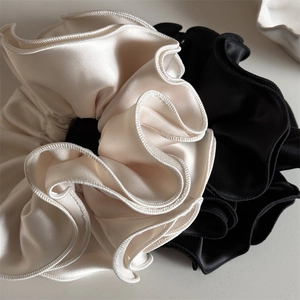 Gros plan de chouchous en satin de qualité supérieure en crème et noir avec bords volantés