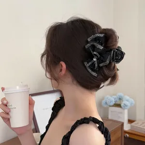 Elegant black bow hair claw clip with silver rhinestone trim for high bun hairstyles