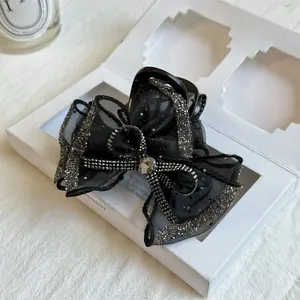 Macro detail of elegant black mesh bow hair claw clip with sparkling rhinestones