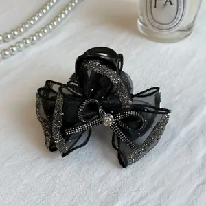 Close-up of elegant black tulle bow hair claw with sparkling rhinestones and crystal detail