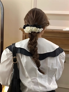Detail of a chic black and white satin bow hair clip styled on a low ponytail