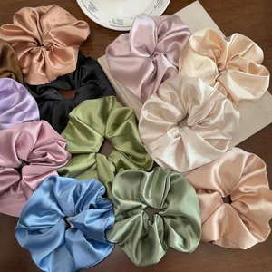 Chouchous élégants en satin surdimensionnés aux couleurs pastel sur une table en bois
