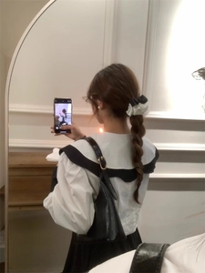Detail view of a large black and white pleated satin bow hair clip on a braided hairstyle
