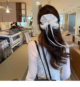 Detailed view of a white satin ballet-style bow scrunchie with elegant long ribbons