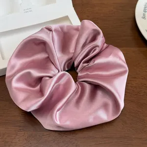 Détail d'un grand chouchou en satin rose avec éclat soyeux sur une table en bois
