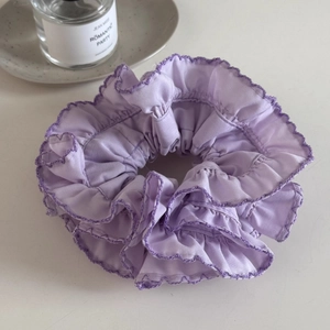 Detailed close-up of purple pleated scrunchie with delicate wavy stitching on white tray