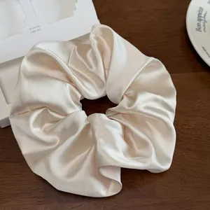 Gros plan d'un chouchou en satin crème élégant avec une texture plissée sur du bois