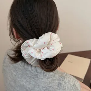 Close-up of oversized cream scrunchie with pink polka dots styled on a bun hairstyle