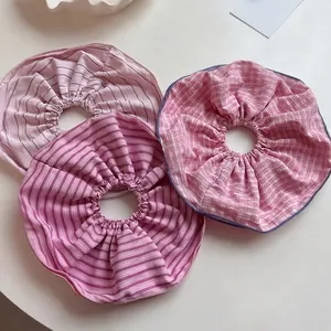 Three pink striped and checkered oversized scrunchies set on a clean white surface