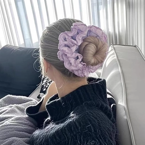 Purple pleated scrunchie with scalloped lace edge styled on a bun hairstyle