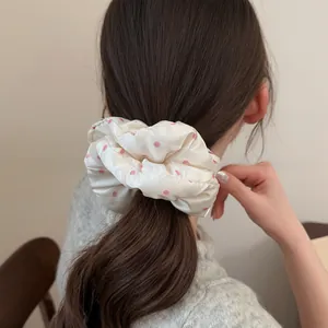 Close-up of a soft satin scrunchie with pink polka dots used in a ponytail hairstyle