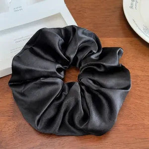 Détail d'un chouchou géant en satin noir avec texture soyeuse et plis élégants