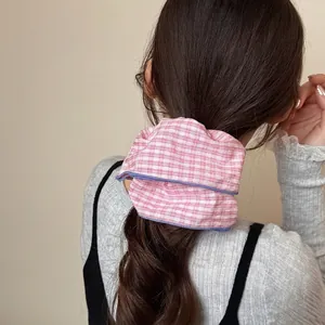 Pink and white checkered scrunchie with blue piping worn on a high ponytail