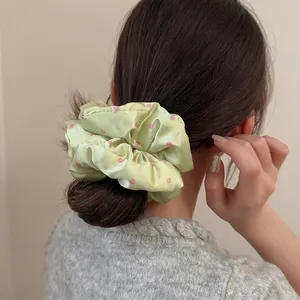 Polka dot green satin scrunchie shown in a low bun hairstyle for daily sweet look