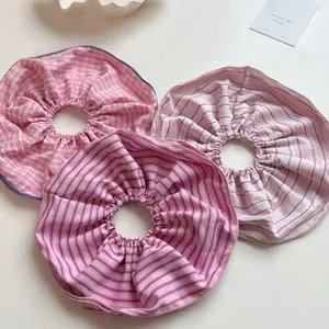 Detail of three oversized striped and checkered pink hair scrunchies in soft cotton fabric