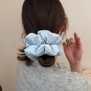Detail of light blue polka dot pillow scrunchie worn on a ponytail for hair styling