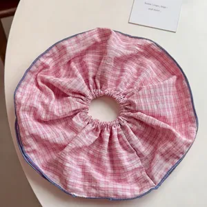 Detailed view of pink and white checkered scrunchie fabric with blue stitching