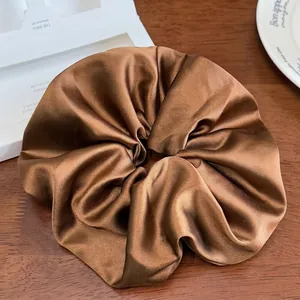 Vue détaillée d'un grand chouchou en satin marron avec texture plissée brillante sur bois