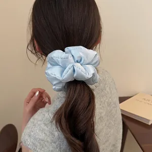 Light blue satin pillow scrunchie for women shown on low ponytail for a soft aesthetic look