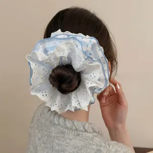 Close-up detail of oversized blue striped lace scrunchie on hair bun with floral embroidery