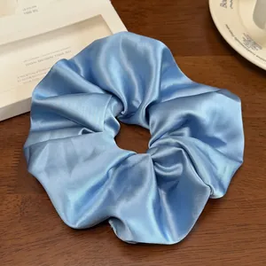 Détail du chouchou en satin bleu ciel avec une texture élégante en soie plissée et douce