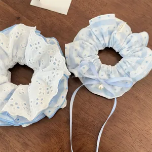 Detail of light blue lace scrunchie set with white embroidery and pearl bow pendant
