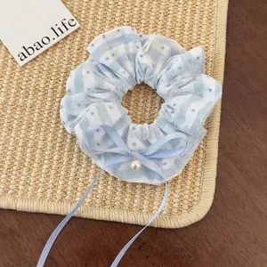 Detailed view of light blue lace scrunchie with white polka dots and pearl charm