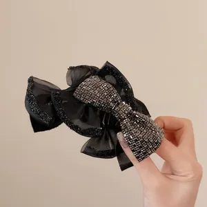 Dettaglio del fermaglio nero con fiocco in rete e strass grigio scuro scintillanti