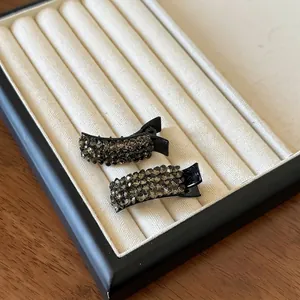 Detail view of two luxury duckbill hair clips with grey rhinestones on velvet