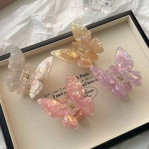 Close-up of four iridescent butterfly hair claws in white, yellow, pink, and purple acetate