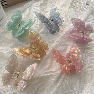 Set of 6 colorful 3D butterfly hair claws in iridescent finishes on white paper