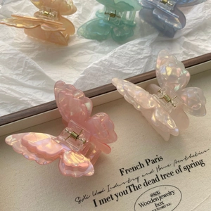 Detailed macro of iridescent 3D butterfly hair claw clips with pearlescent acetate texture