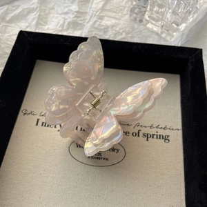 Detail of iridescent double-layered butterfly hair claw clip with golden metal spring