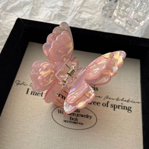 Detail of a pink iridescent butterfly hair claw clip with golden metal spring on display