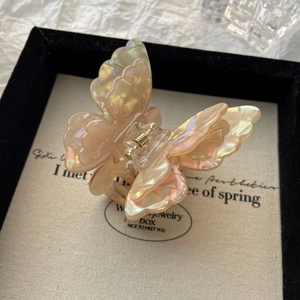 Macro detail of iridescent 3D butterfly hair claw clip with golden metal spring
