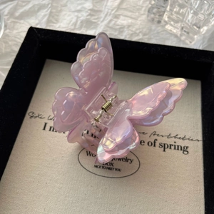 Detailed close-up of pink butterfly hair claw with pearlescent finish in a jewelry box