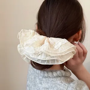 Close-up of cream lace hair scrunchie with gold polka dots on a ponytail hairstyle