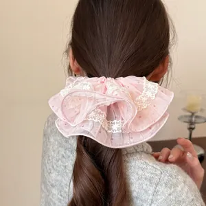 Close-up of pink scrunchie with white lace edges and red polka dots on wavy hair
