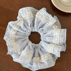 Detail of light blue lace scrunchie with pink polka dots and floral embroidery on wood