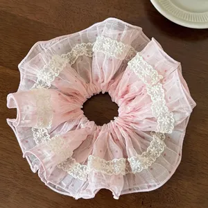 Close-up of pink polka dot chiffon scrunchie with white floral lace trim on wood