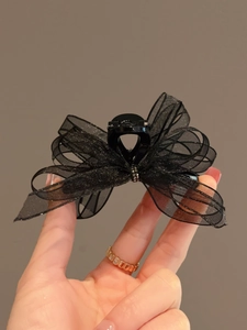 Close-up of elegant black organza bow hair claw clip with shimmering glitter and rhinestones