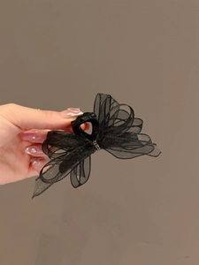 Detail of layered black organza bow hair claw with shimmering edges and glossy finish