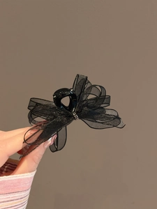 Detail of elegant black organza bow hair claw with shimmering sequins and rhinestone accents