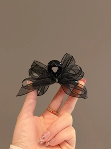 Detailed view of an elegant black organza bow hair claw clip with crystal center decor