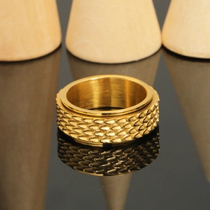 Macro view of gold spinner ring featuring detailed dragon scale relief and polished finish