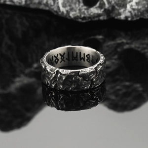 Vista macro di un anello vintage argento con trama rocciosa e rune nordiche incise