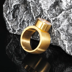 Macro shot of gold stainless steel ring with brushed texture and bezel-set zircon stone